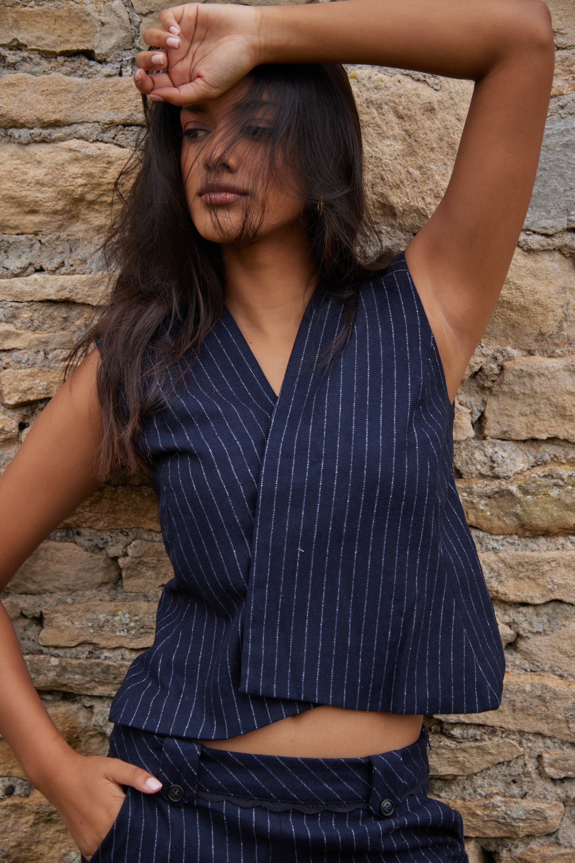 Woman wearing a navy pinstripe suit against a stone wall.